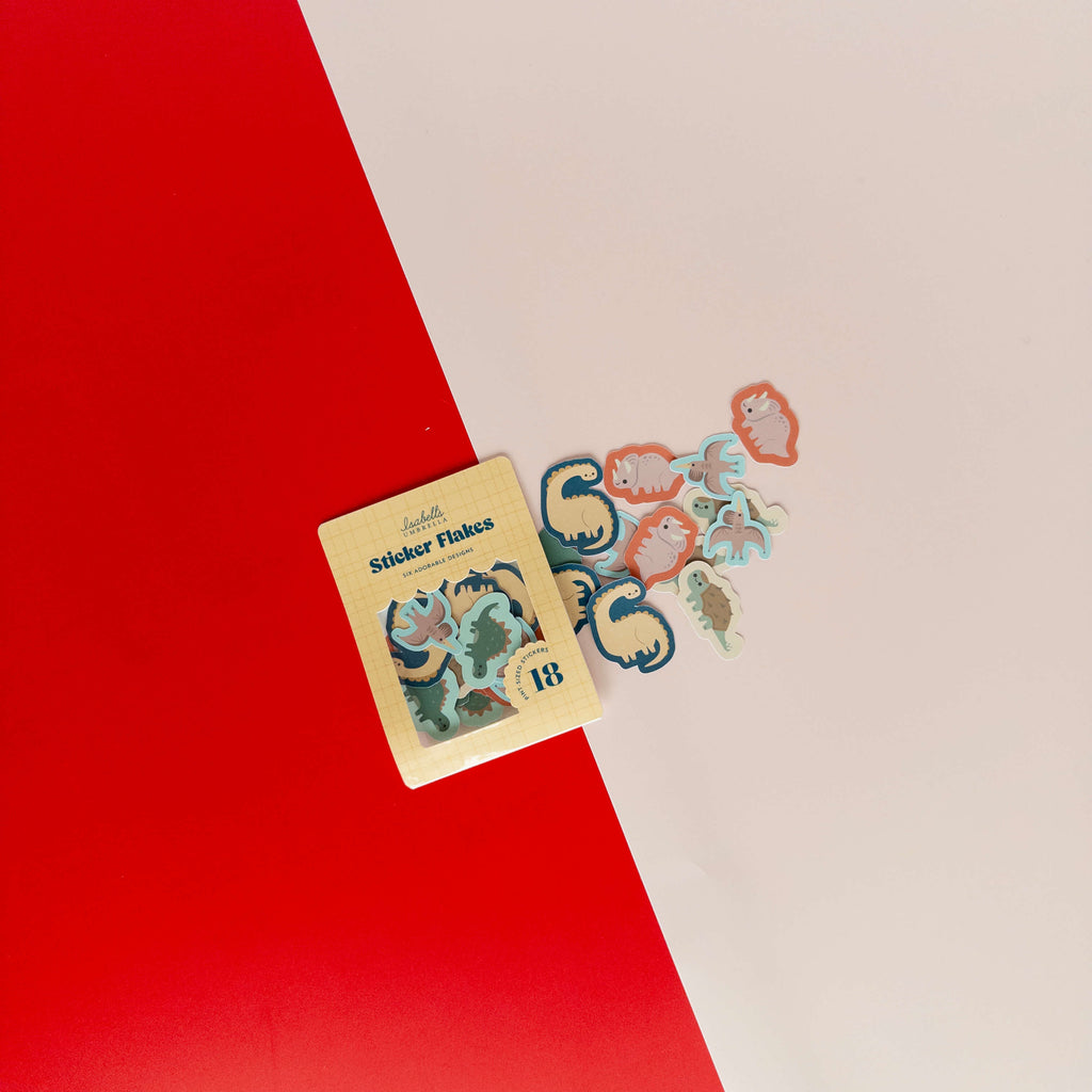 Cute dinosaur sticker flakes scattered around their packaging on a red and cream background.