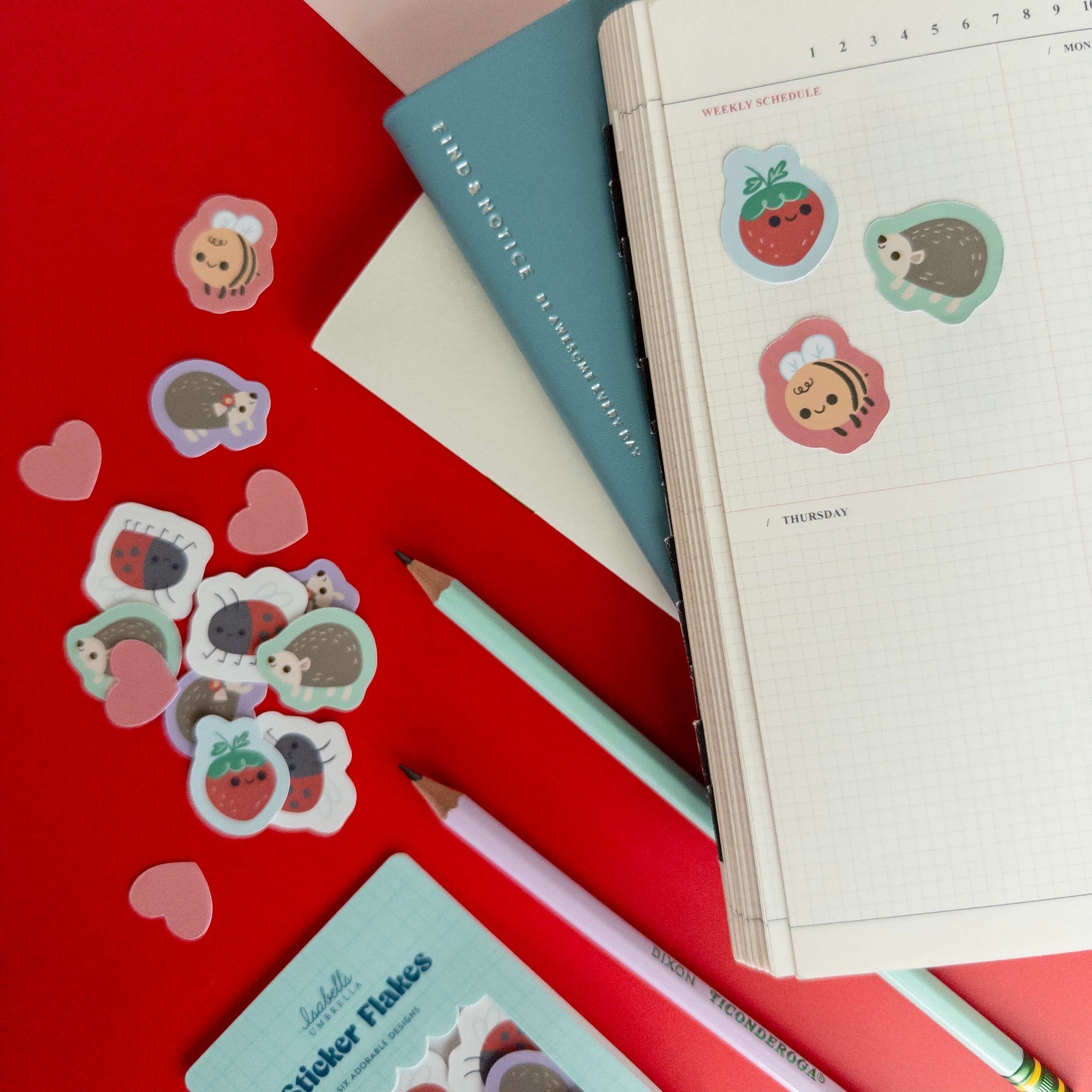 Cute hedgehog stickers decorating an open grid notebook surrounded by colorful stationery.