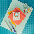 Cute roly poly acrylic journal clip displayed on its backing card with colorful paper, washi tape, and pens.