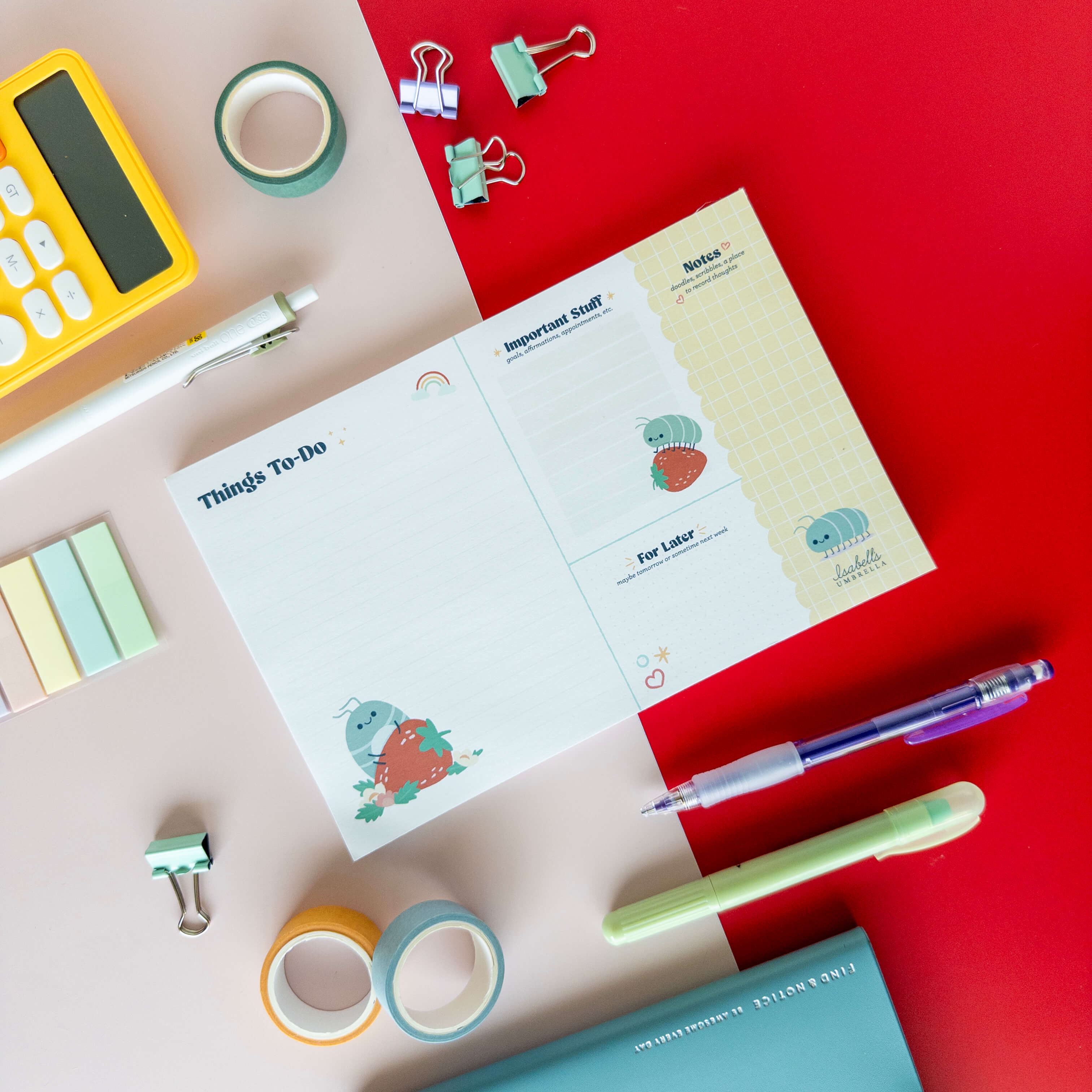 Cute roly poly daily planner notepad displayed on a colorful desk with pens, binder clips, and stationery.