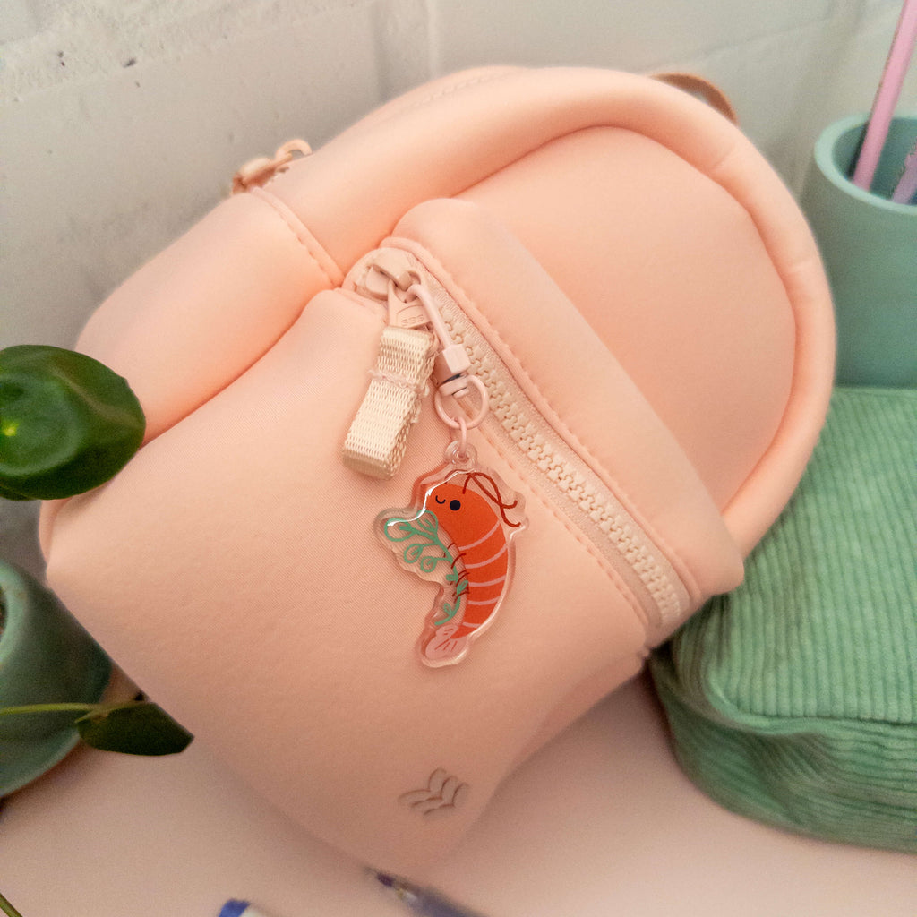 Small pink backpack with a shrimp charm on a light gray background