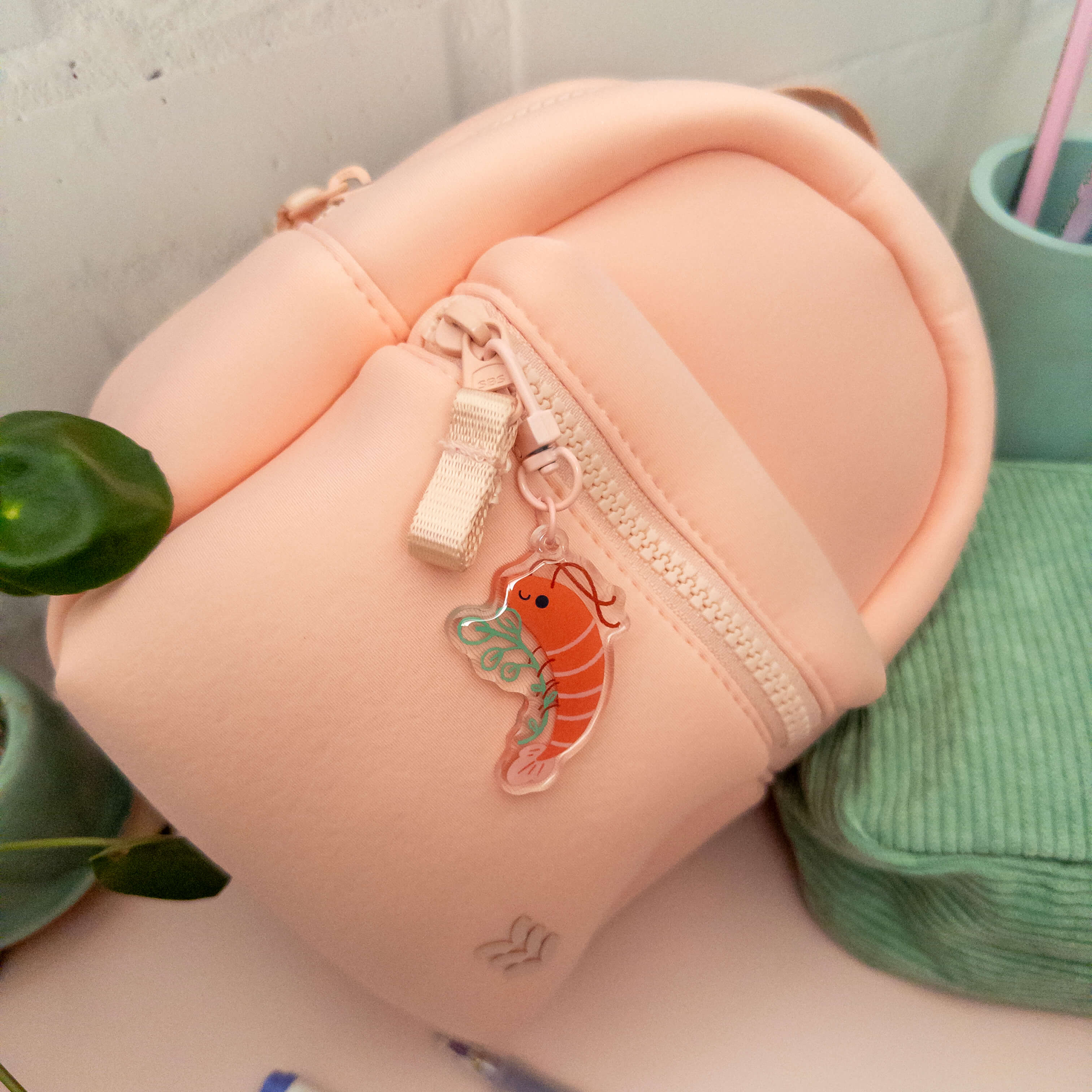 Small pink backpack with a shrimp charm on a light gray background