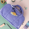 Cute Ankylosaurus acrylic keychain attached to purple bag.