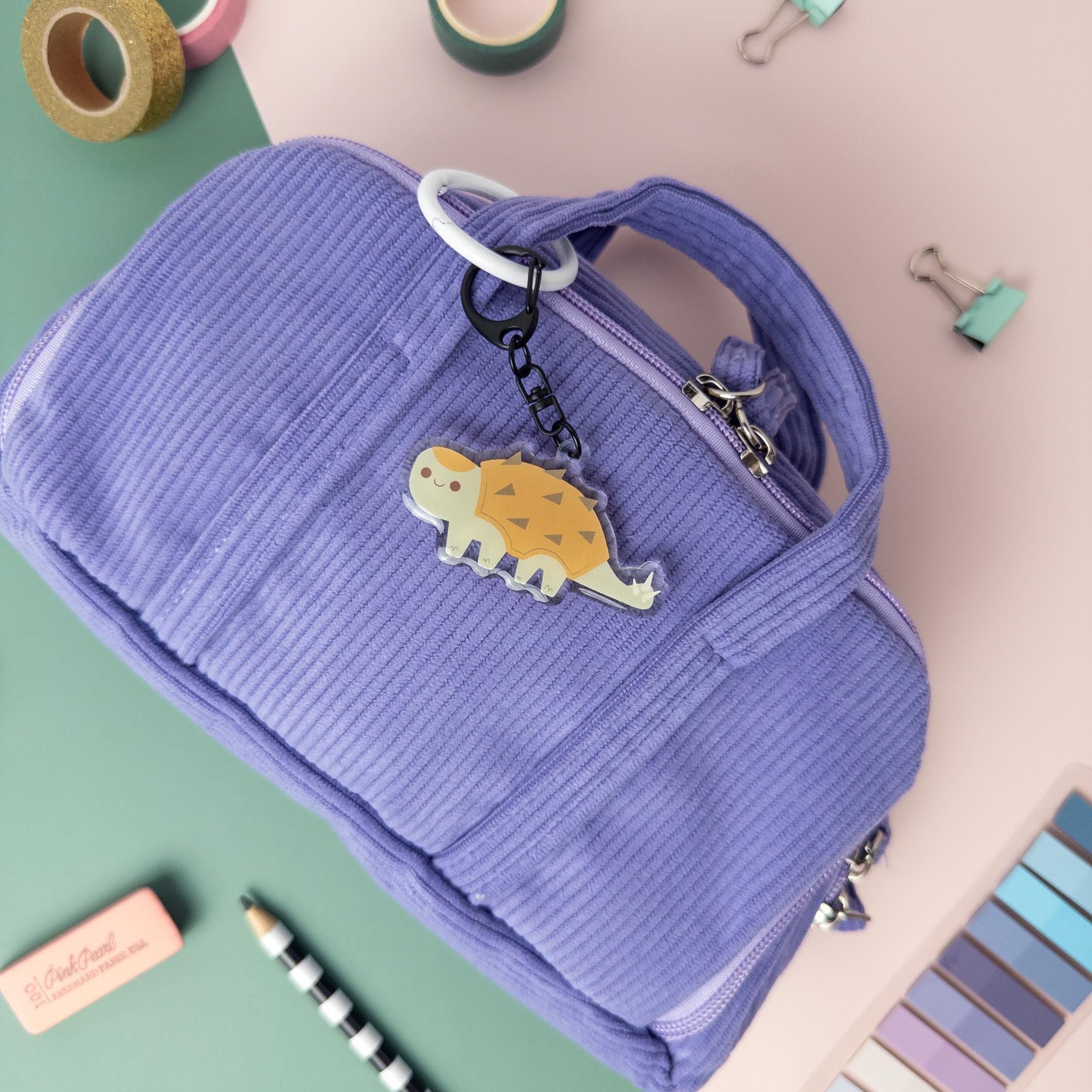 Cute Ankylosaurus acrylic keychain attached to purple bag.