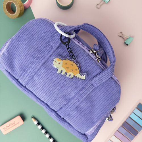 Cute Ankylosaurus acrylic keychain attached to purple bag.