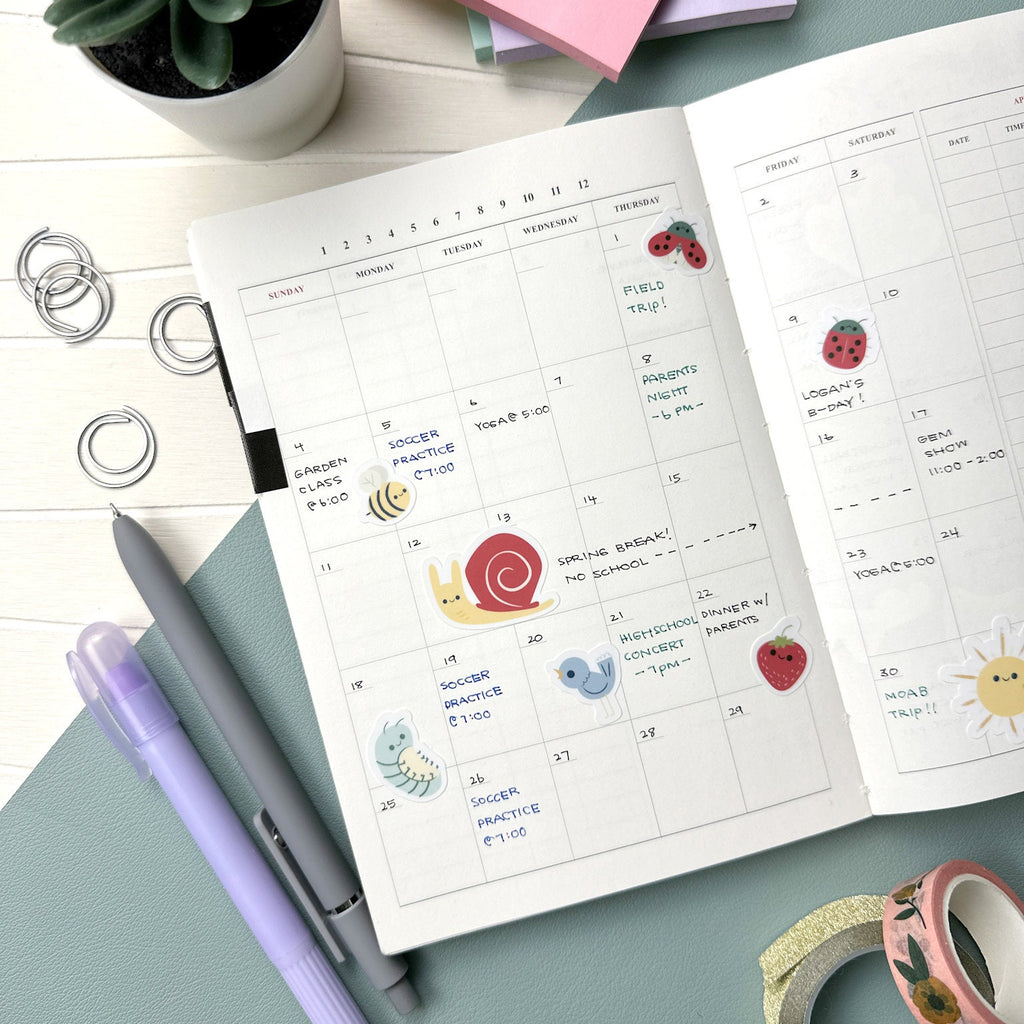 Overhead calendar shot showcasing several stickers including a bee, sunshine, ladybugs, and bird.