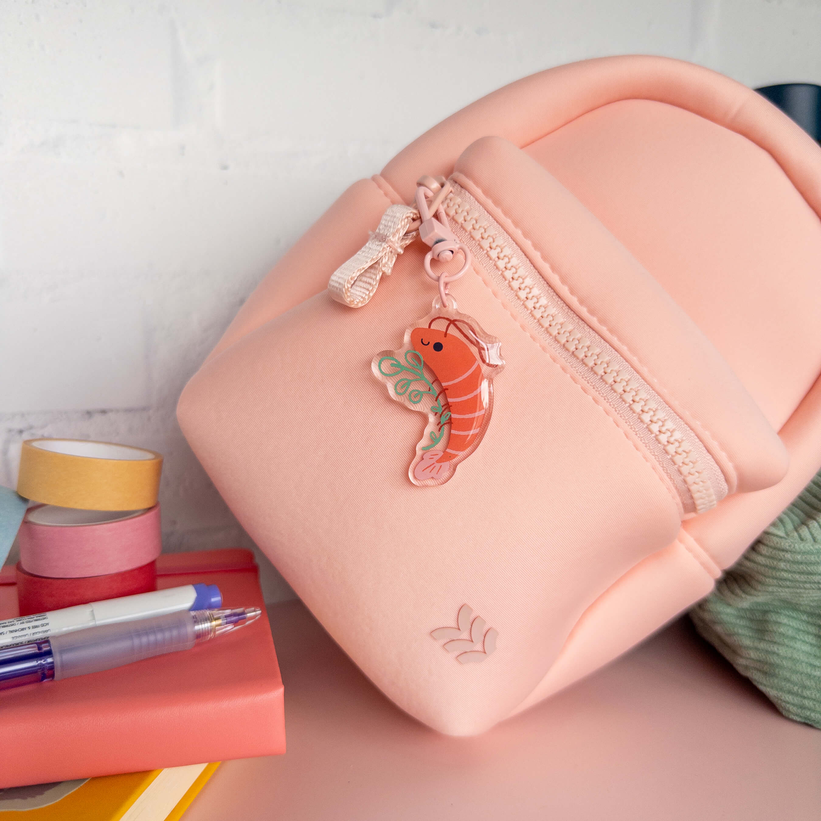 Small pink backpack with a shrimp keychain charm on a white background