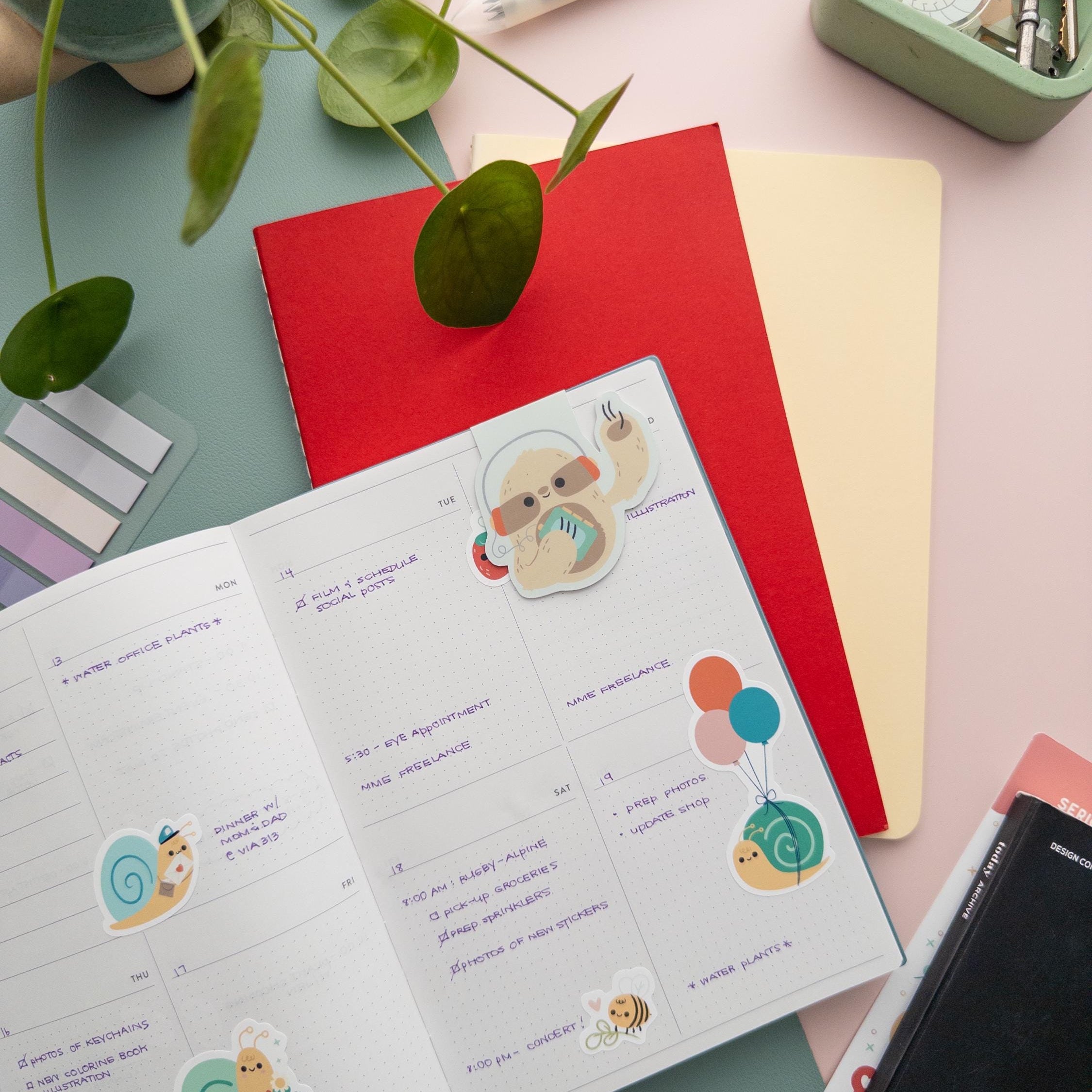 Sloth with Walkman magnetic bookmark clipped on an open calendar page, cute retro reading accessory for cozy readers and students.