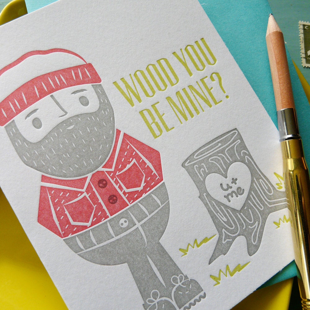 A detailed shot of a cute illustrated lumberjack letterpress card with “Wood You Be Mine” message, handmade Valentine or love notecard with coordinating envelope.