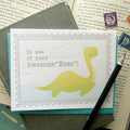 Card with a Loch Ness Monster illustration photographed on top of an open book.