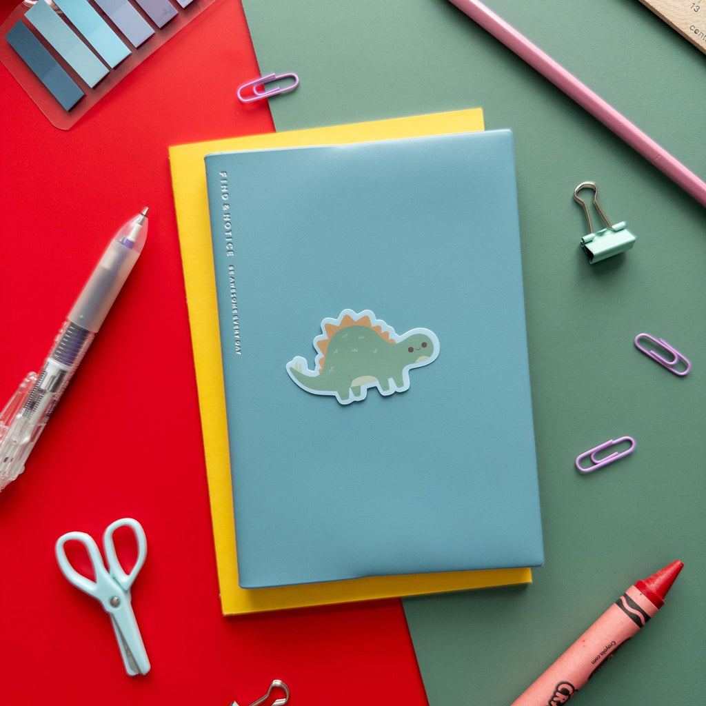 Notebook with a dinosaur sticker on a colorful background with stationery items