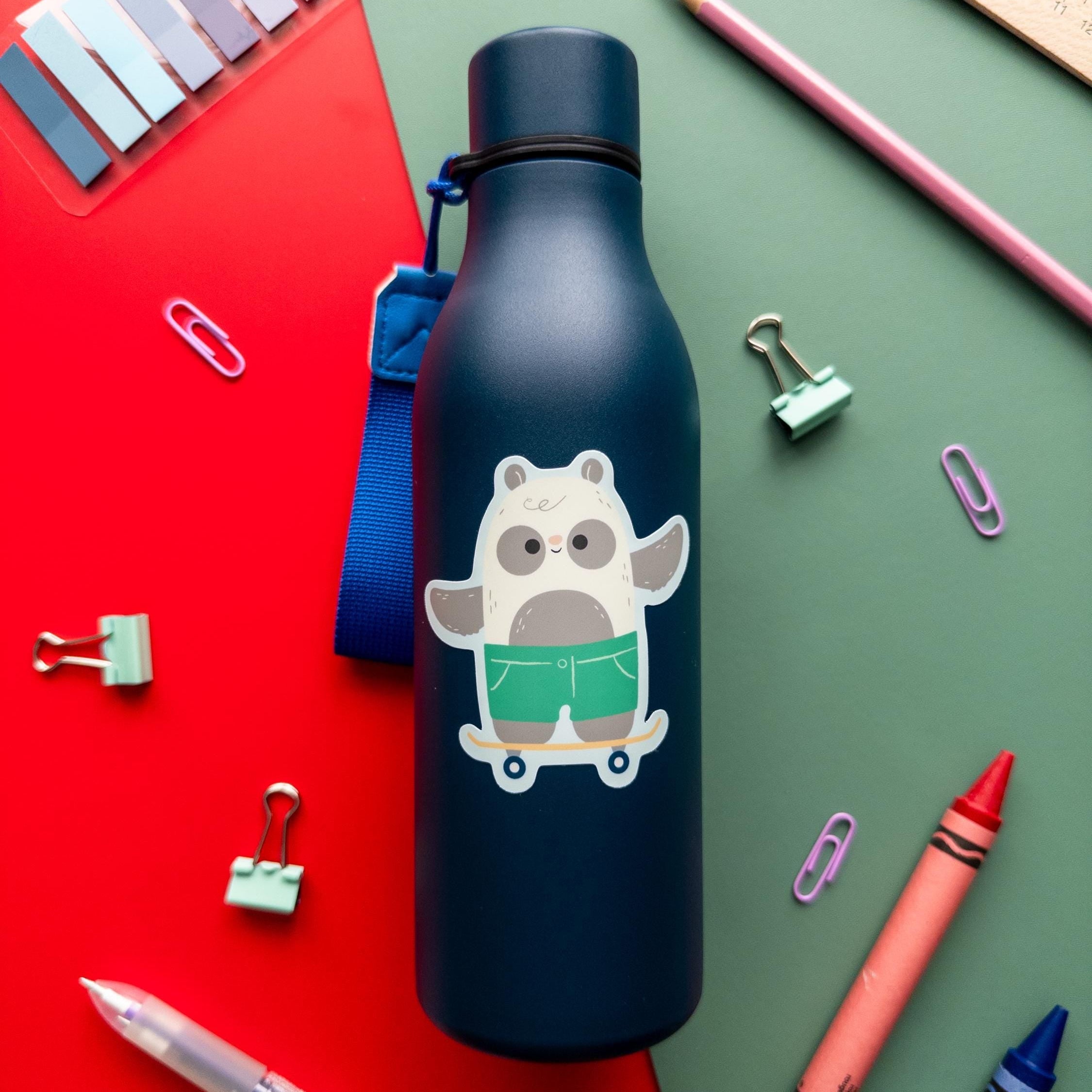 A cute skateboarding panda vinyl sticker stuck to a blue water bottle placed on a red and green background.
