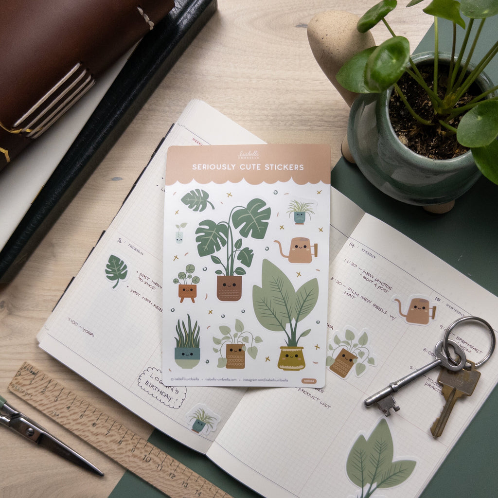 Set of cute illustrated house plant stickers placed on top of open weekly planner.