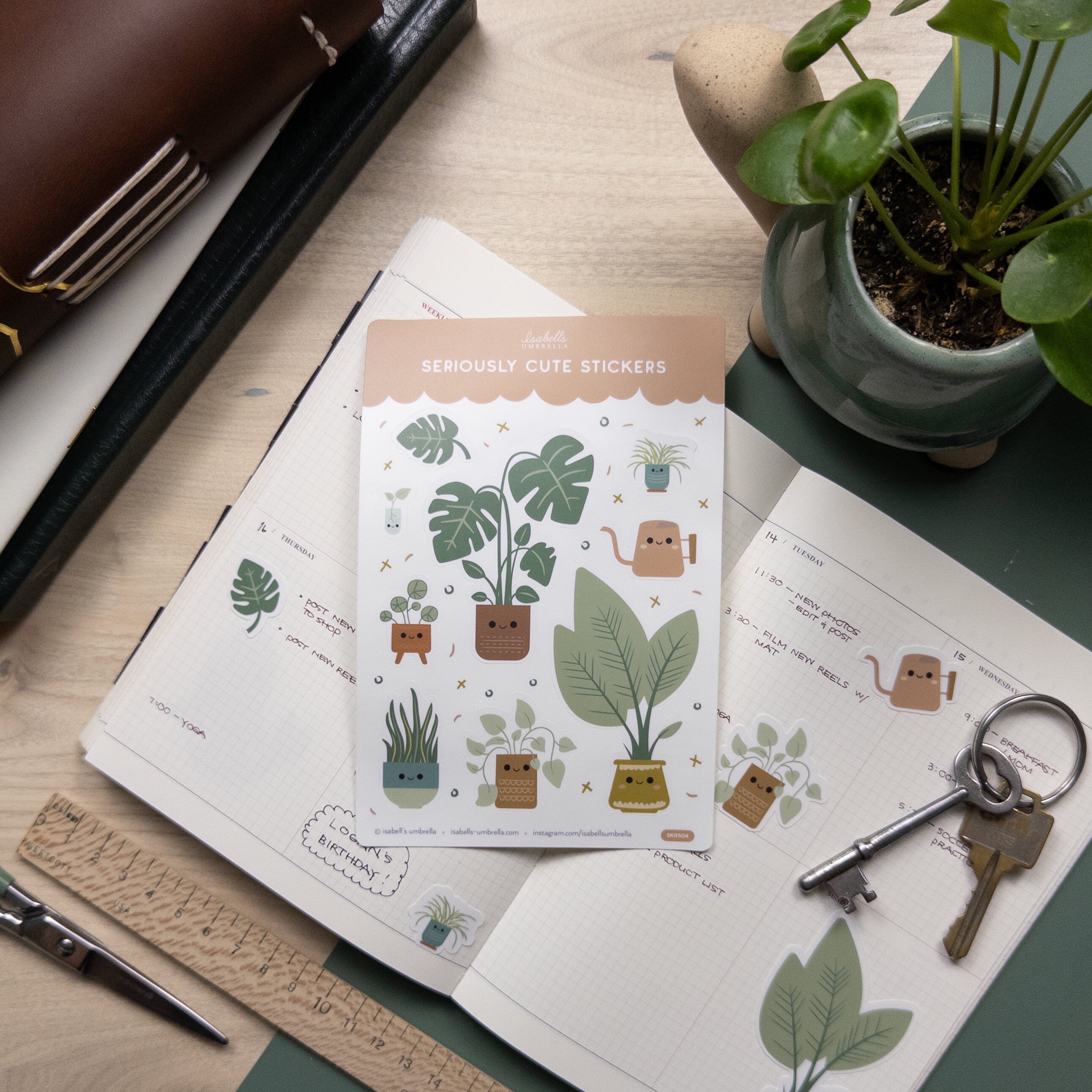Set of cute illustrated house plant stickers placed on top of open weekly planner.