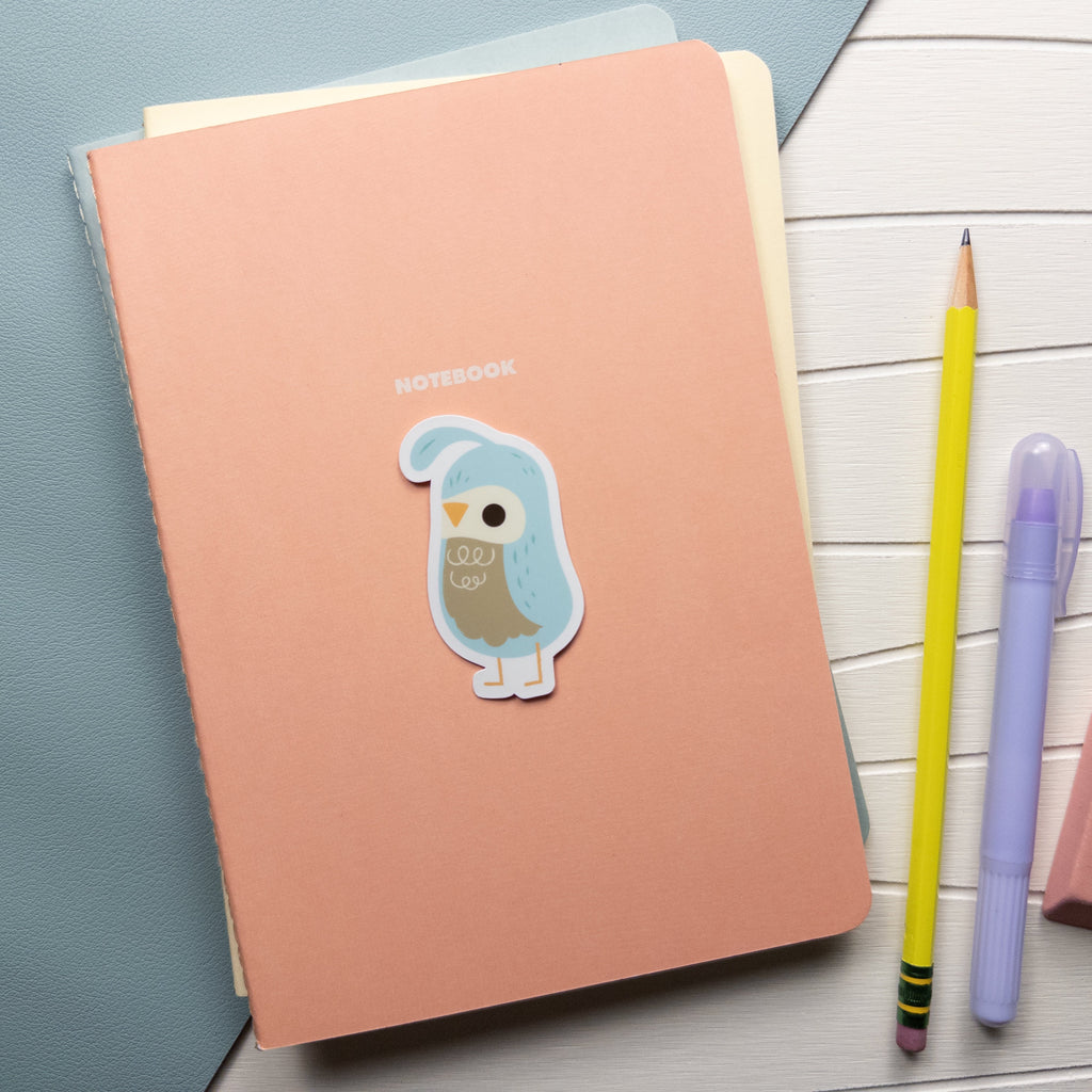 Cute illustrated quail vinyl sticker set on top of a pile of small pastel colored notebooks.