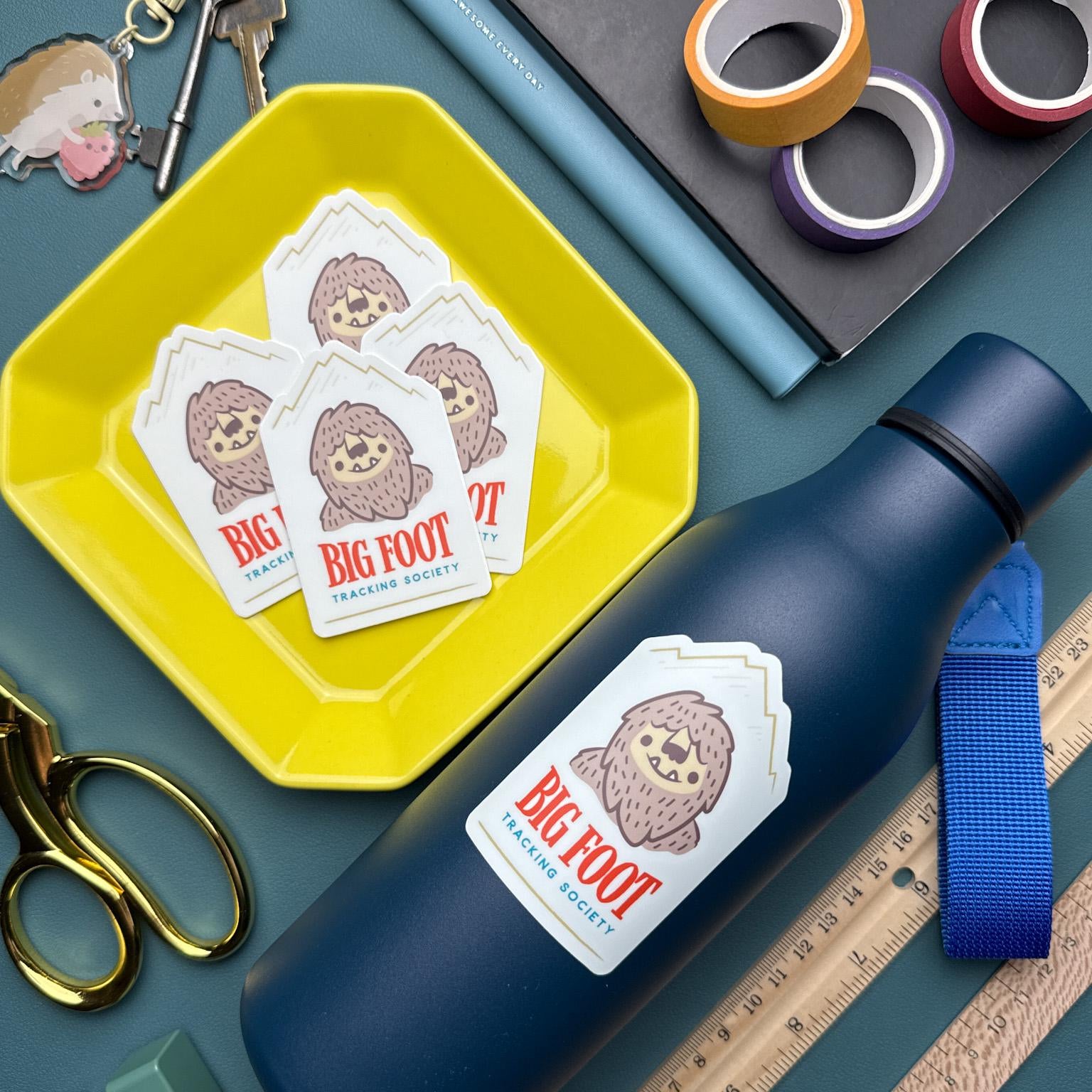 stack of big foot tracking society stickers featuring an illustration of big foot with mountains in the background